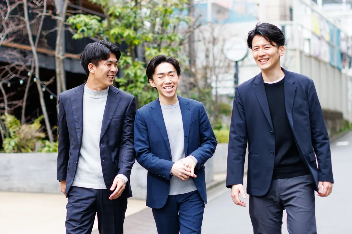 屋外で笑顔で歩く3人